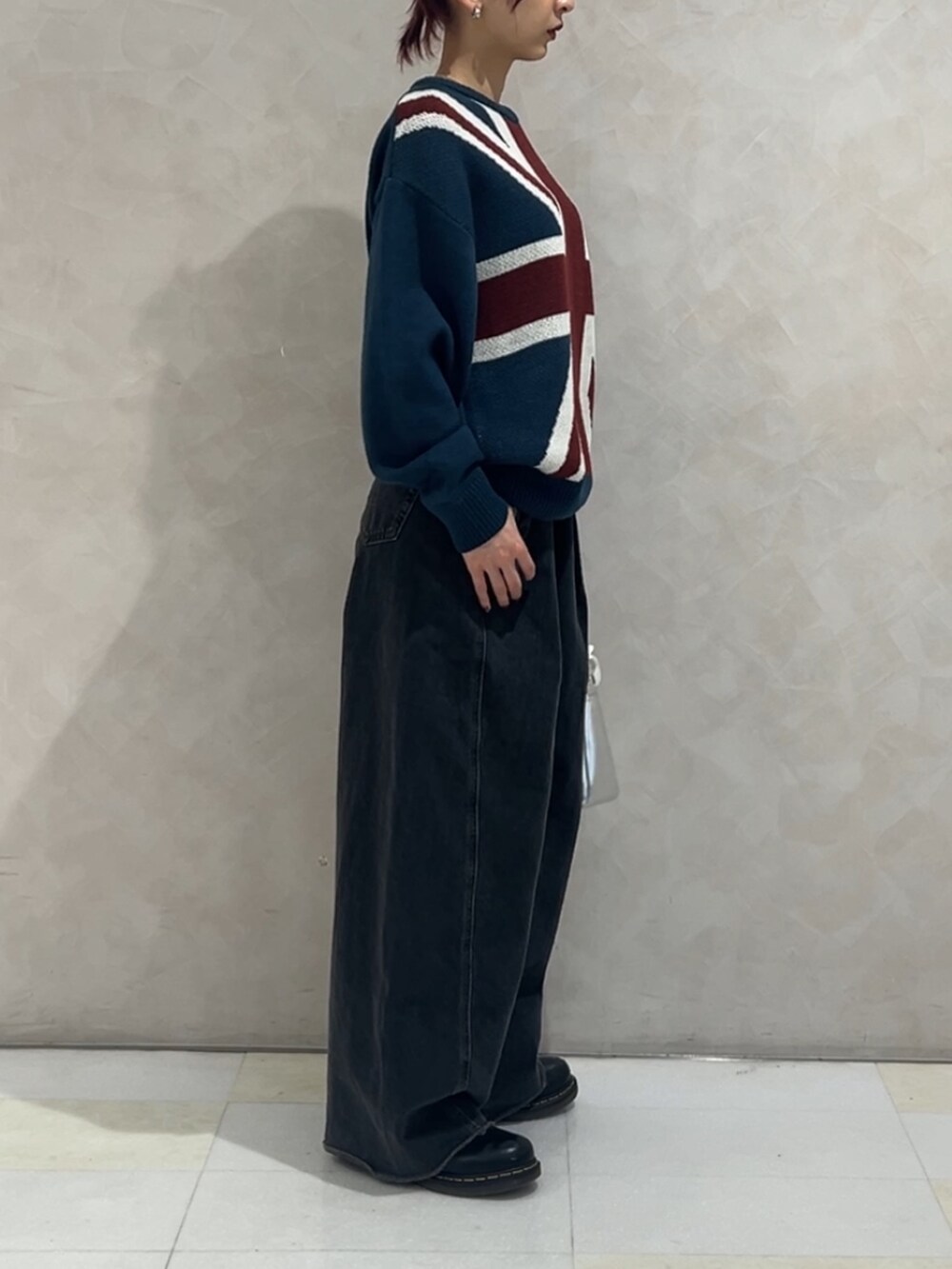 ブルー系のニット/セーター、ブラック系のデニムパンツ、シルバー系のハンドバッグを着用したレディースの冬コーディネートの4枚目の写真