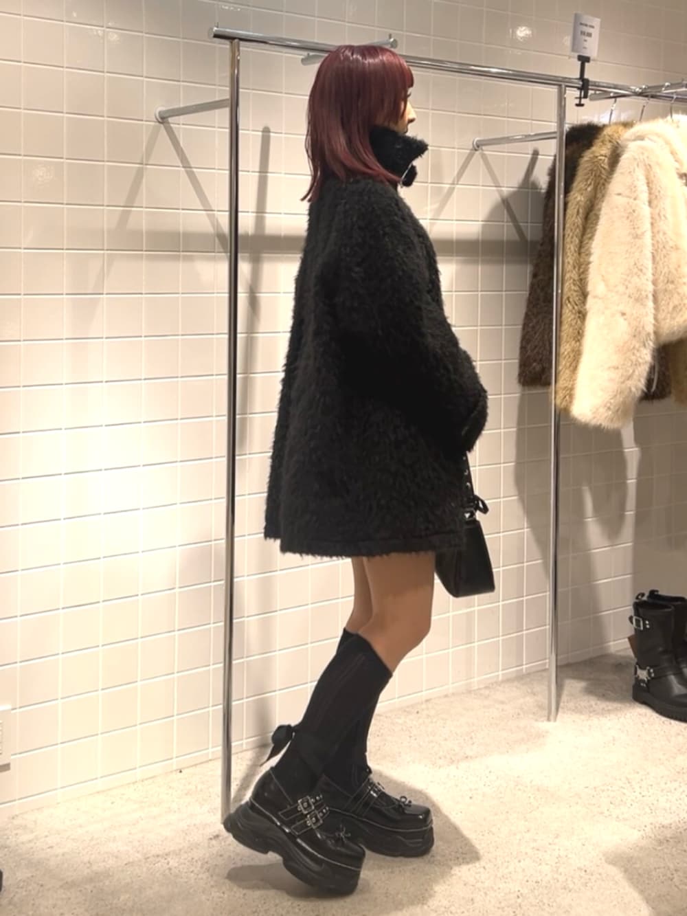 ブラック系のスニーカー、ブラック系のステンカラーコート、ブラック系のハンドバッグを着用したレディースの冬コーディネートの2枚目の写真