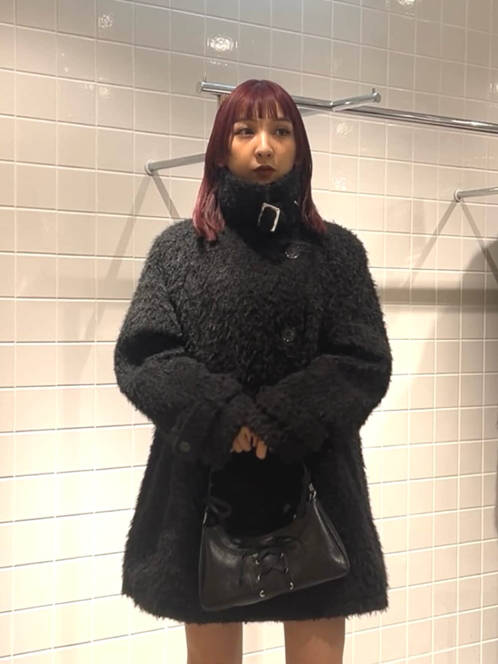 ブラック系のスニーカー、ブラック系のステンカラーコート、ブラック系のハンドバッグを着用したレディースの冬コーディネートの5枚目の写真