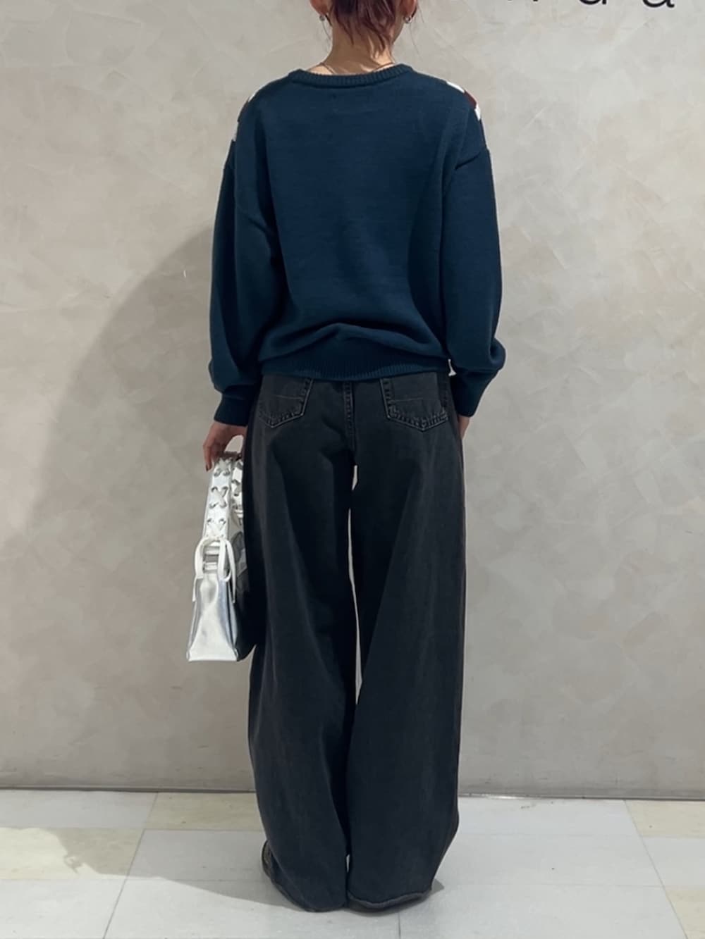ブルー系のニット/セーター、ブラック系のデニムパンツ、シルバー系のハンドバッグを着用したレディースの冬コーディネートの3枚目の写真