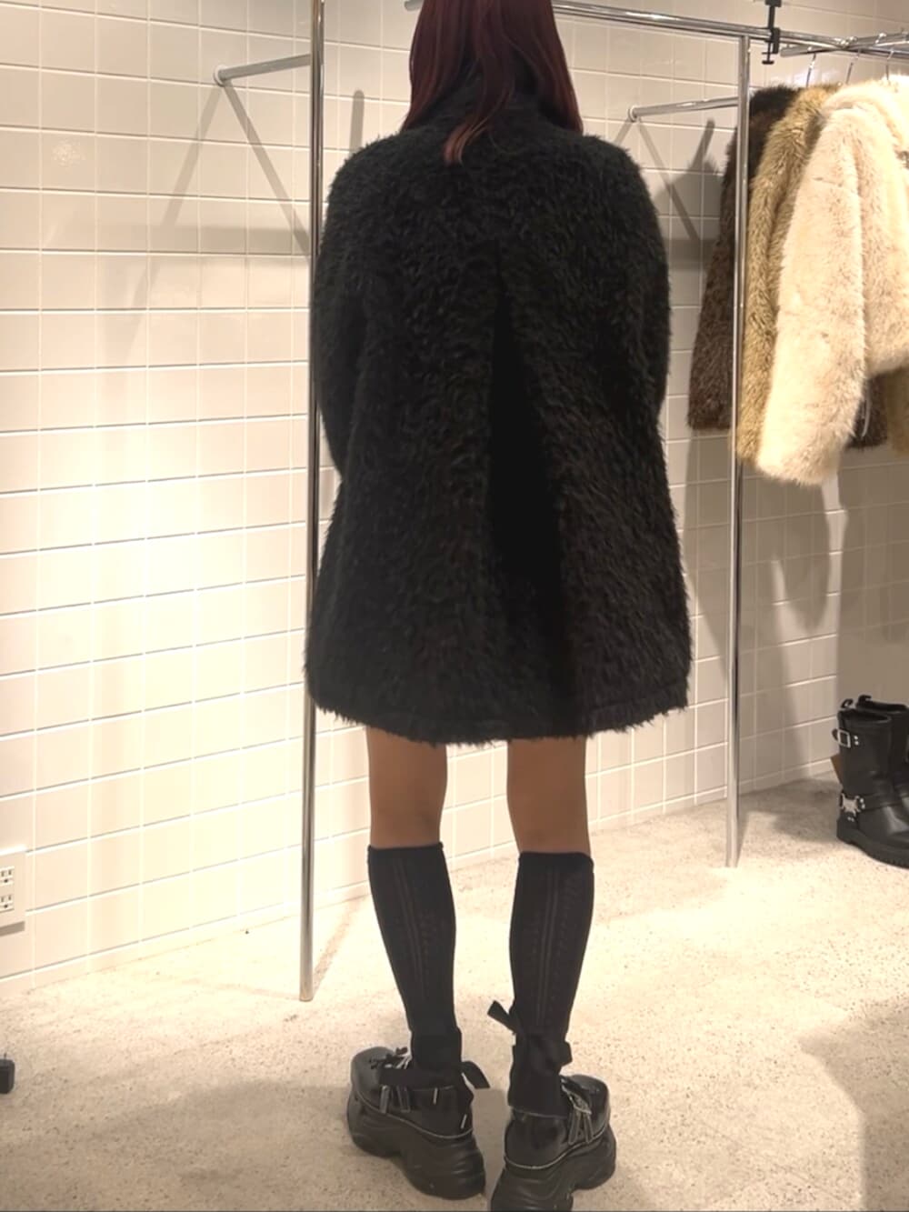 ブラック系のスニーカー、ブラック系のステンカラーコート、ブラック系のハンドバッグを着用したレディースの冬コーディネートの4枚目の写真