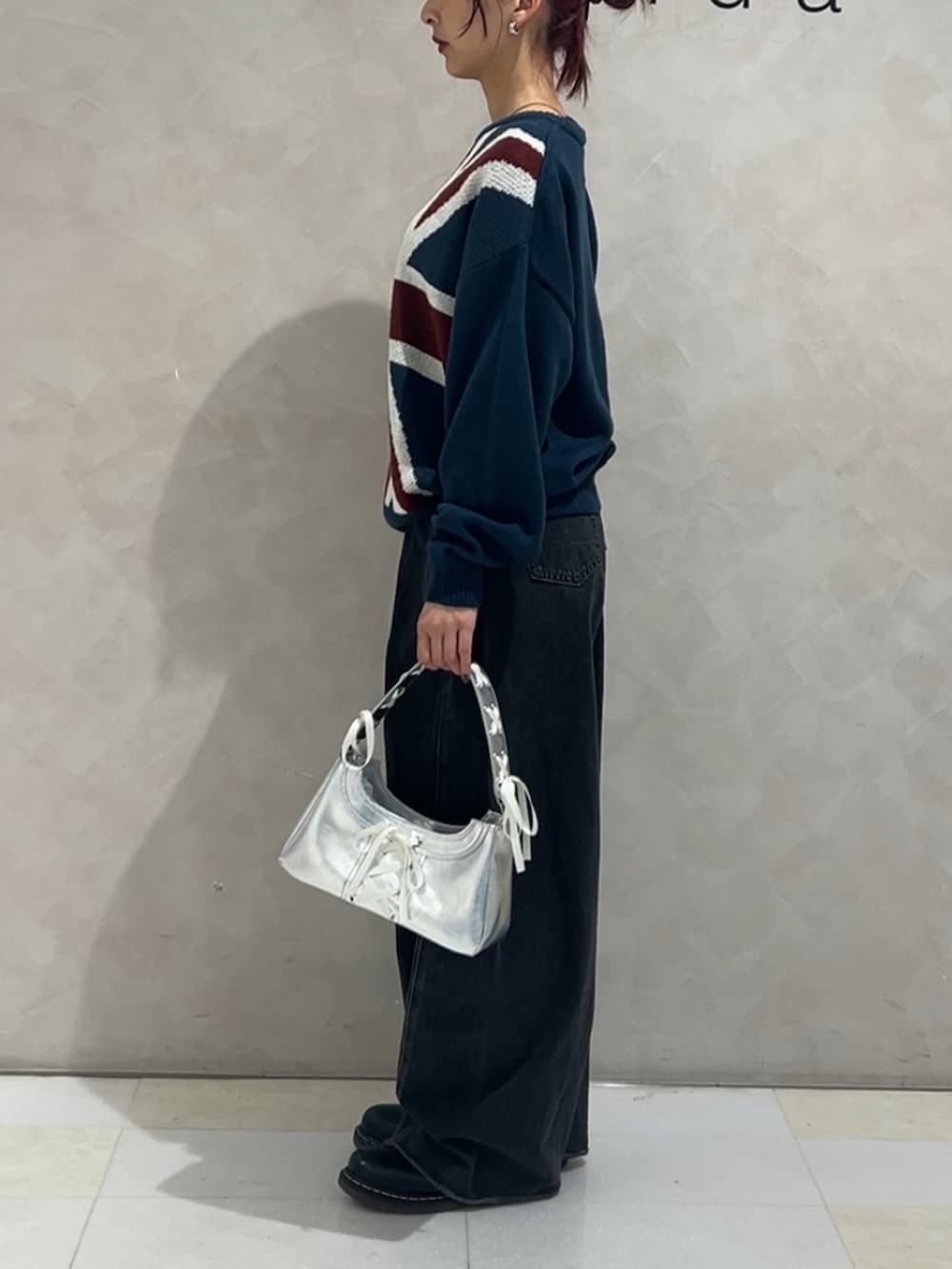 ブルー系のニット/セーター、ブラック系のデニムパンツ、シルバー系のハンドバッグを着用したレディースの冬コーディネートの2枚目の写真