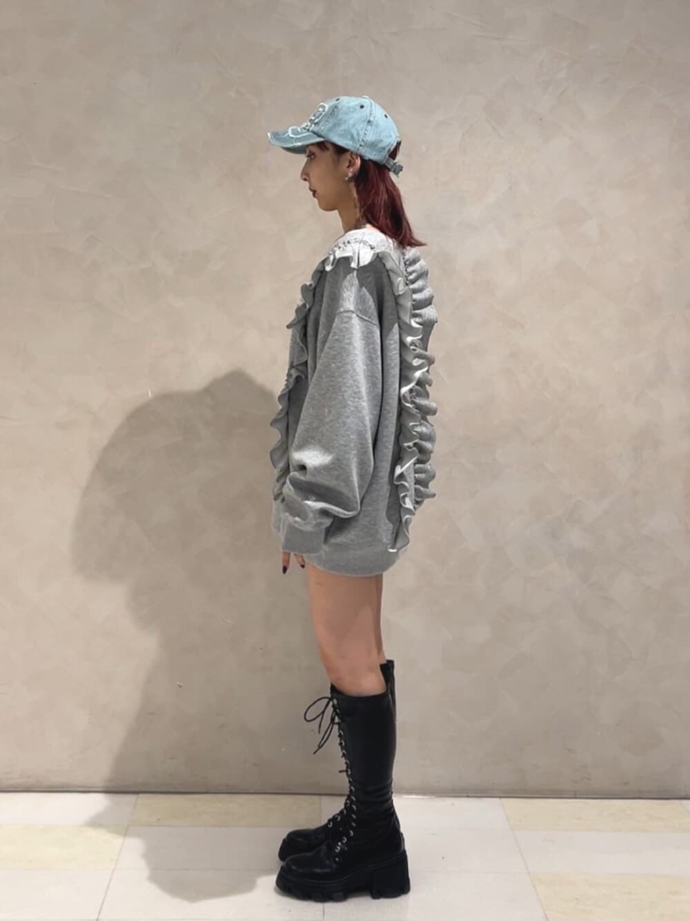 ブラック系のブーツ、グレー系のスウェット、ブルー系のキャップを着用したレディースの秋コーディネートの2枚目の写真