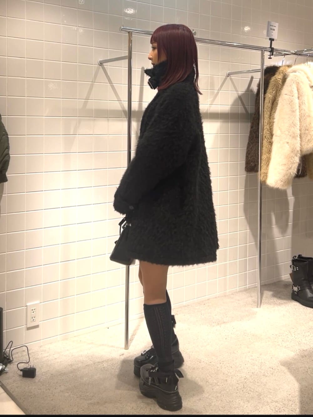 ブラック系のスニーカー、ブラック系のステンカラーコート、ブラック系のハンドバッグを着用したレディースの冬コーディネートの3枚目の写真