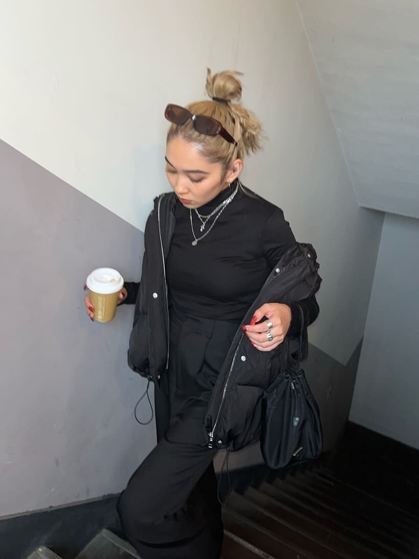 ブラック系のスラックス、ブラック系のTシャツ/カットソー、ブラック系のダウンジャケット/コートを着用したレディースの秋コーディネートの2枚目の写真