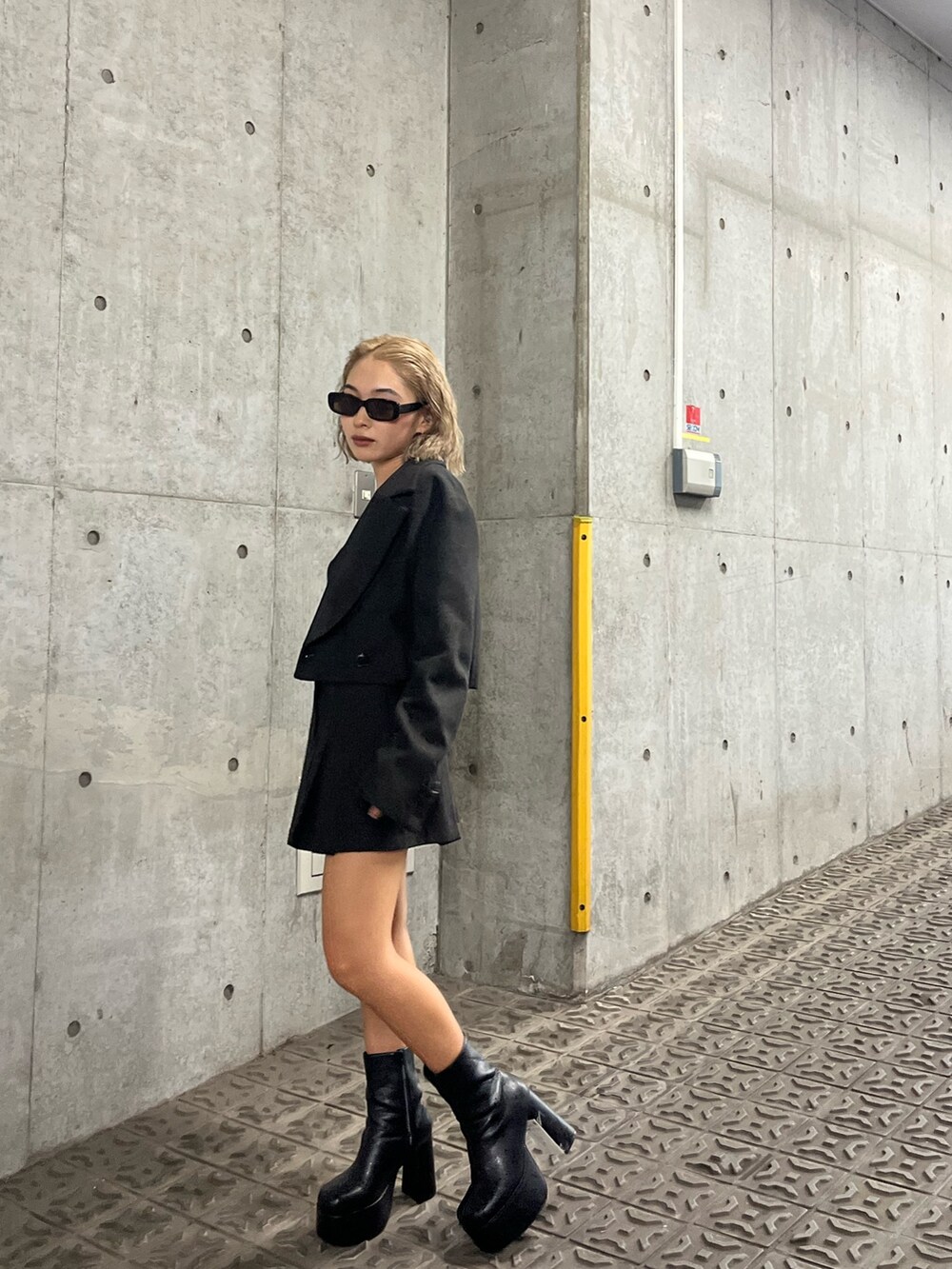 ブラウン系のテーラードジャケット、ブラウン系のスカート、ブラック系のブーツを着用したレディースの夏コーディネートの2枚目の写真