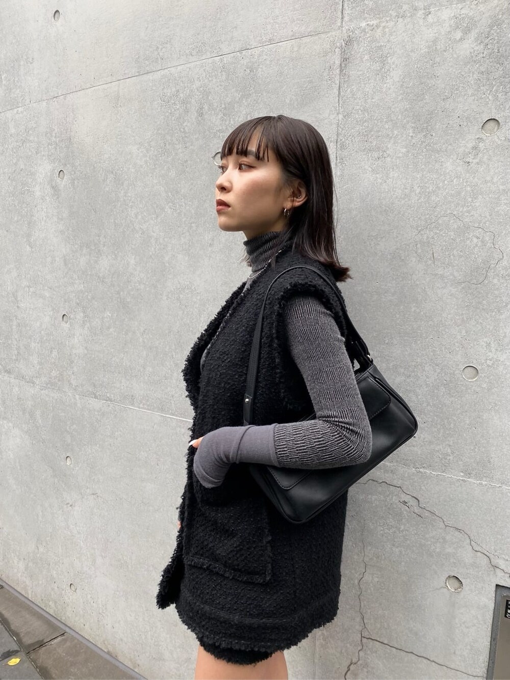 ブラック系のベスト、ブラック系のスカート、ブラウン系のブーツを着用したレディースの夏コーディネートの3枚目の写真