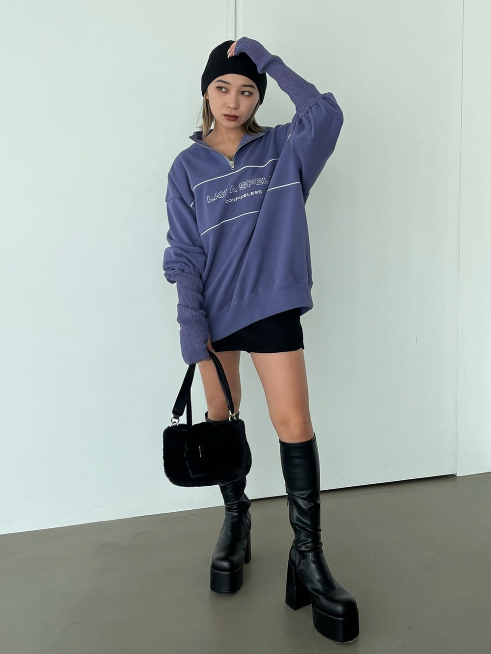 パープル系のスウェット、ブラック系のブーツ、ブラック系のハンドバッグを着用したレディースの秋コーディネートの2枚目の写真