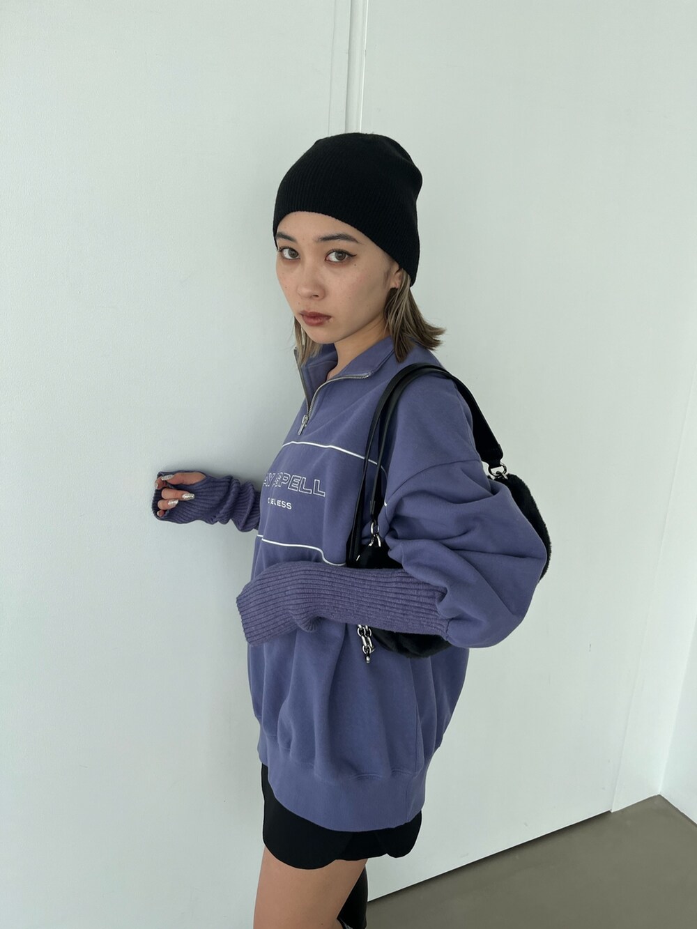 パープル系のスウェット、ブラック系のブーツ、ブラック系のハンドバッグを着用したレディースの秋コーディネートの3枚目の写真