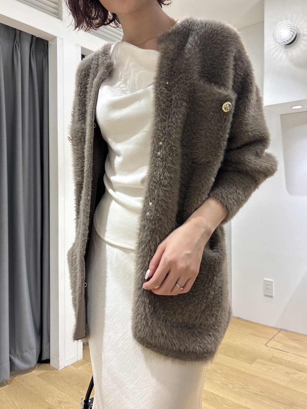 ホワイト系のスカート、ブラウン系のカーディガン/ボレロ、ホワイト系のニット/セーターを着用したレディースの秋コーディネートの5枚目の写真