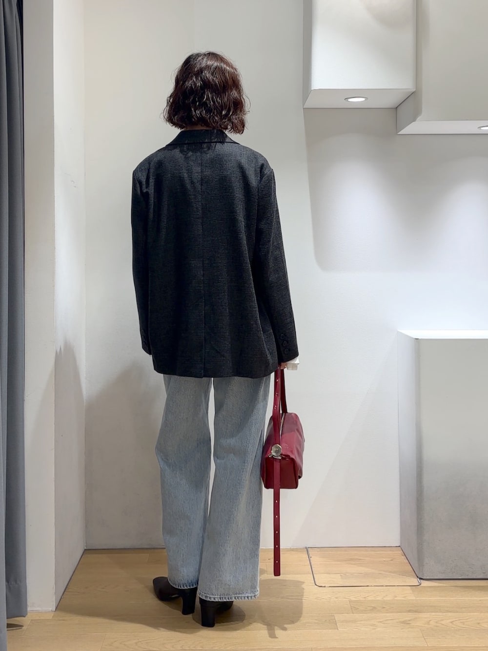 グレー系のテーラードジャケット、ブラック系のニット/セーター、レッド系のハンドバッグを着用したレディースの秋コーディネートの4枚目の写真