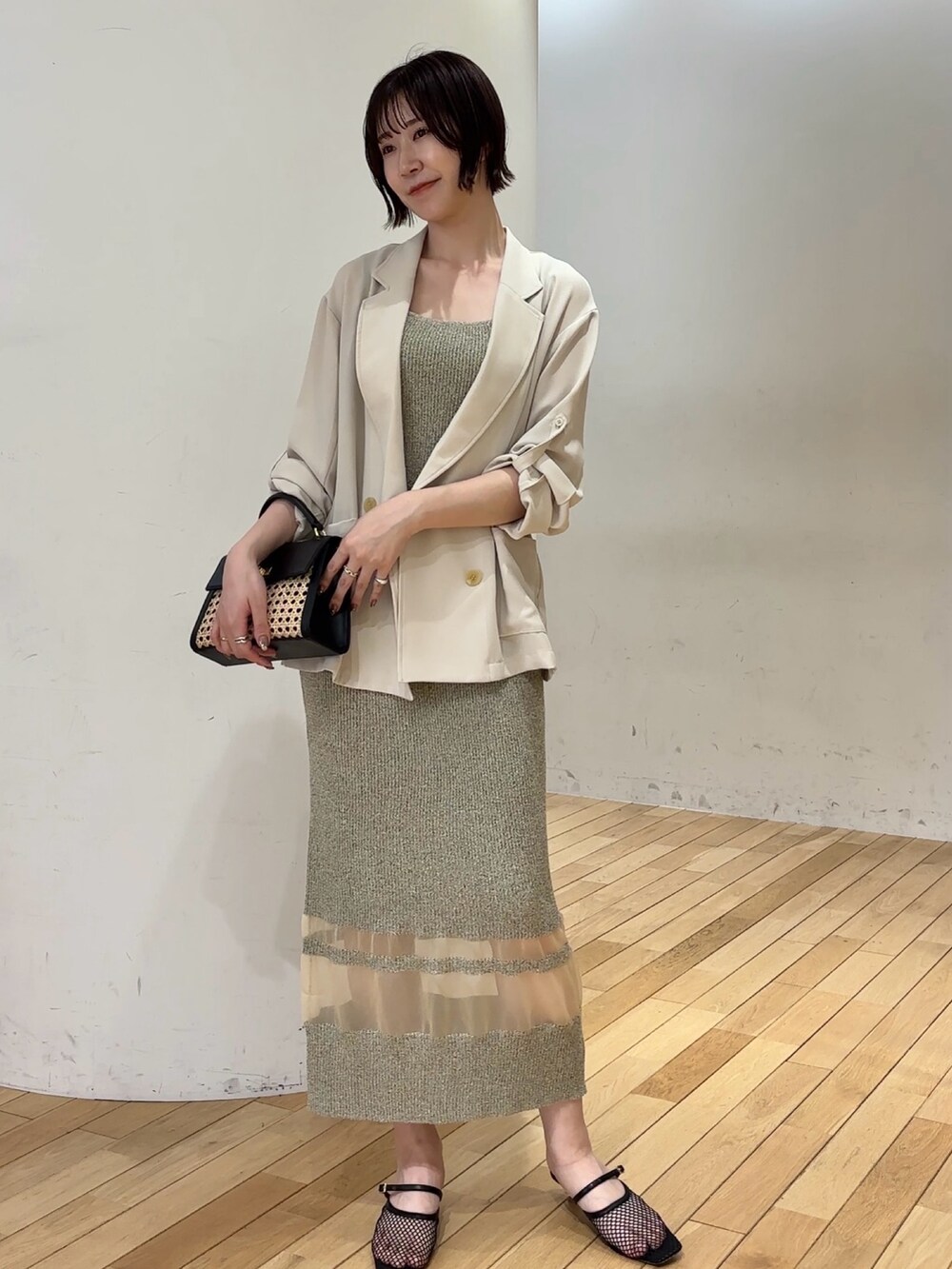 ベージュ系のワンピース、ブラウン系のハンドバッグ、ホワイト系のサンダルを着用したレディースの春コーディネートの6枚目の写真