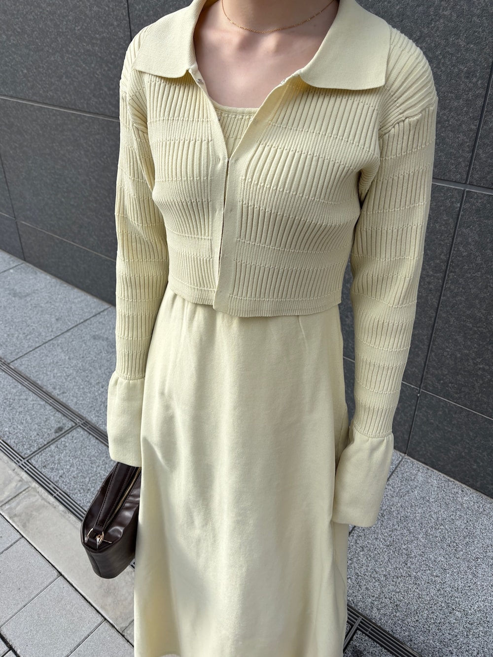 イエロー系のワンピース、ブラウン系のハンドバッグ、シルバー系のパンプスを着用したレディースの冬コーディネートの7枚目の写真