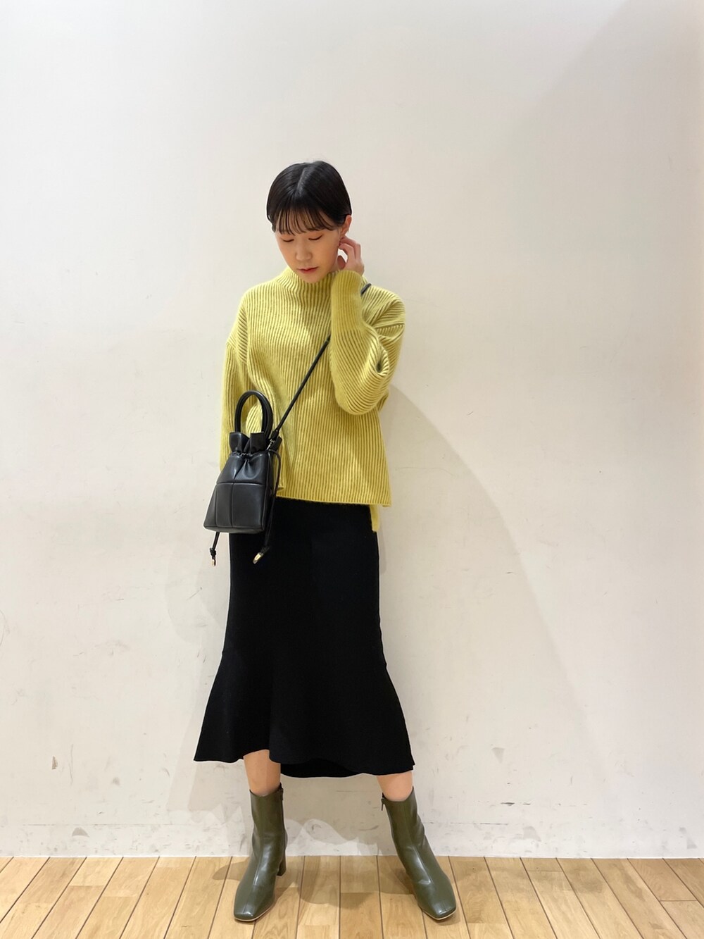 イエロー系のニット/セーター、ブラック系のスカート、ブラック系のハンドバッグを着用したレディースの冬コーディネートの5枚目の写真