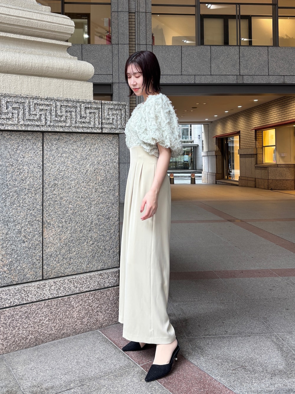 グリーン系のパンツドレス、ブラック系のパンプス、ブラック系のハンドバッグを着用したレディースの冬コーディネートの2枚目の写真