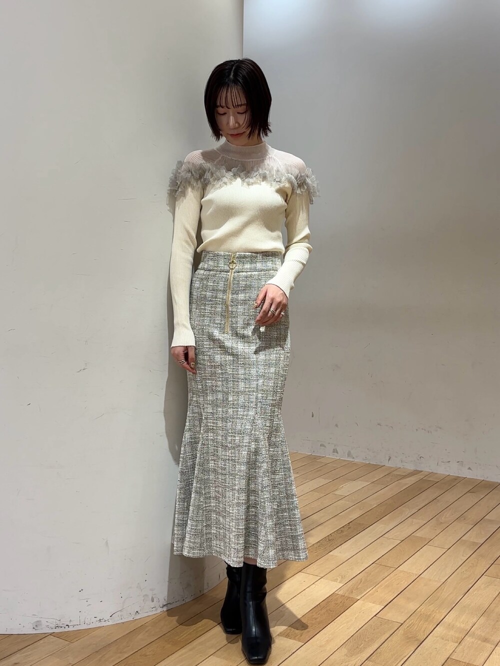 ブラック系のブーツ、ホワイト系のニット/セーター、ホワイト系のスカートを着用したレディースの冬コーディネートの2枚目の写真