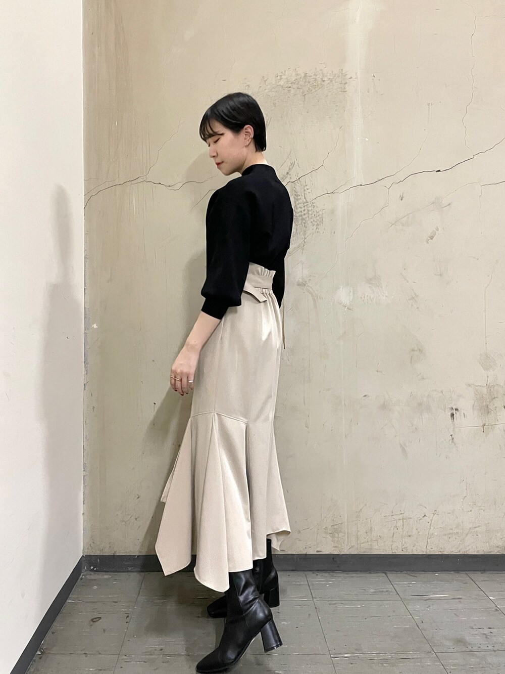 ベージュ系のスカート、ブラック系のニット/セーター、ブラック系のブーツを着用したレディースの秋コーディネートの4枚目の写真