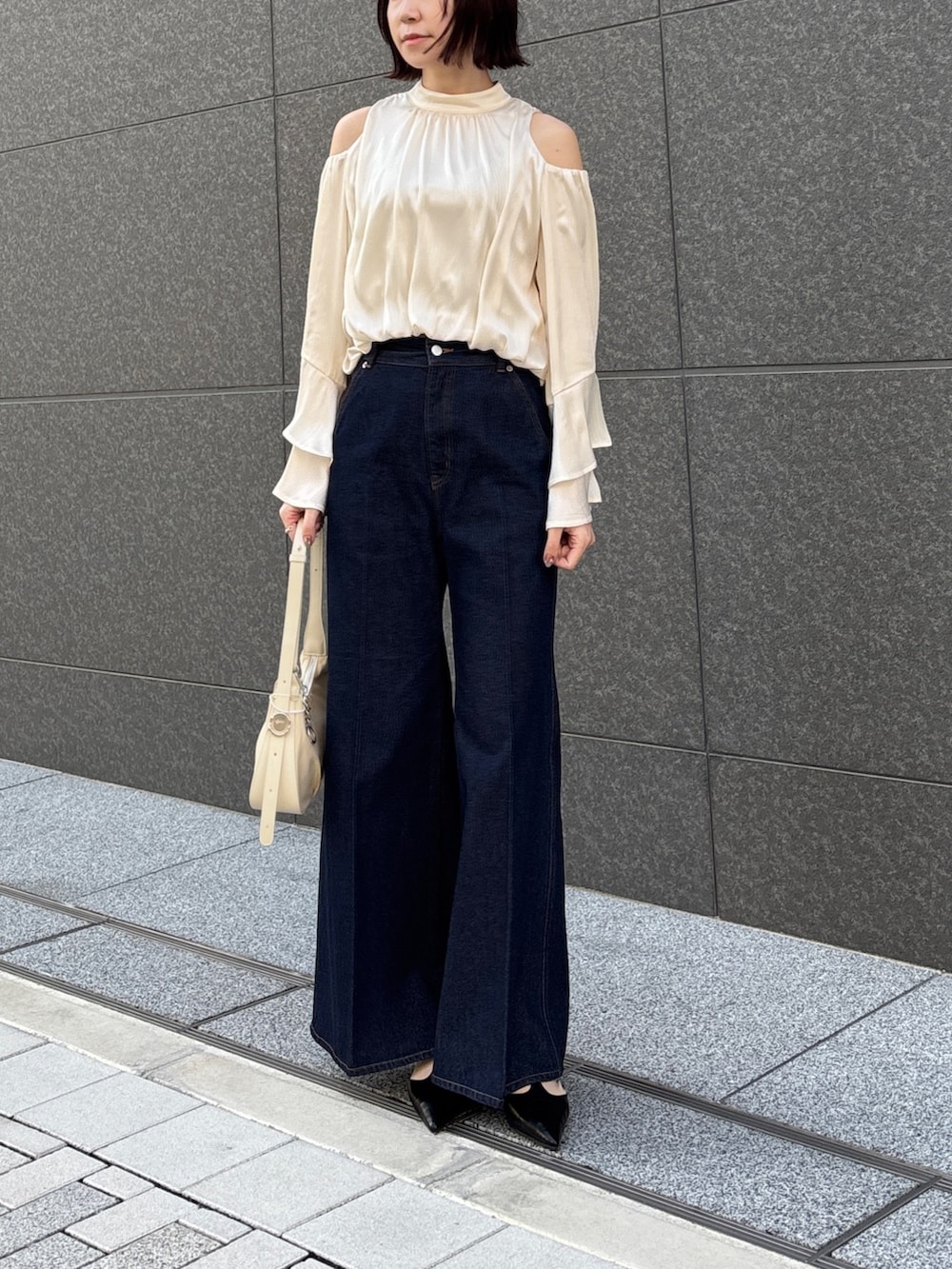 ホワイト系のシャツ/ブラウス、ホワイト系のハンドバッグ、ベージュ系のテーラードジャケットを着用したレディースの春コーディネートの4枚目の写真