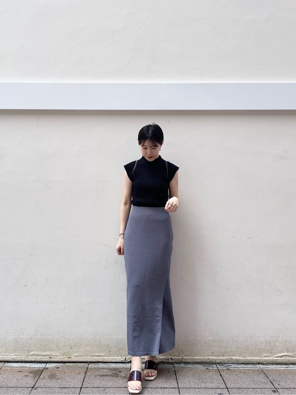 ホワイト系のサンダル、ブルー系のスカート、ブラック系のニット/セーターを着用したレディースの夏コーディネートの2枚目の写真