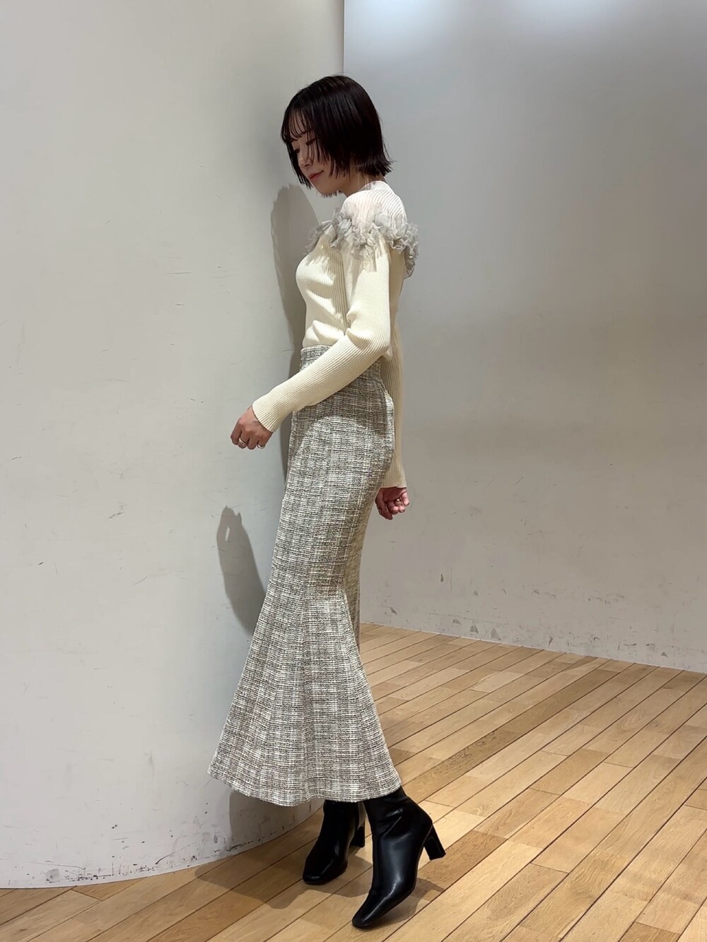 ブラック系のブーツ、ホワイト系のニット/セーター、ホワイト系のスカートを着用したレディースの冬コーディネートの3枚目の写真