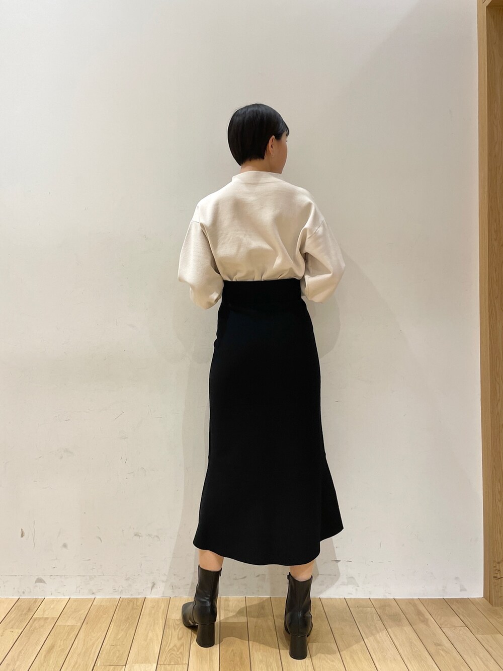 ブラック系のスカート、ホワイト系のニット/セーター、ブラック系のブーツを着用したレディースの冬コーディネートの5枚目の写真