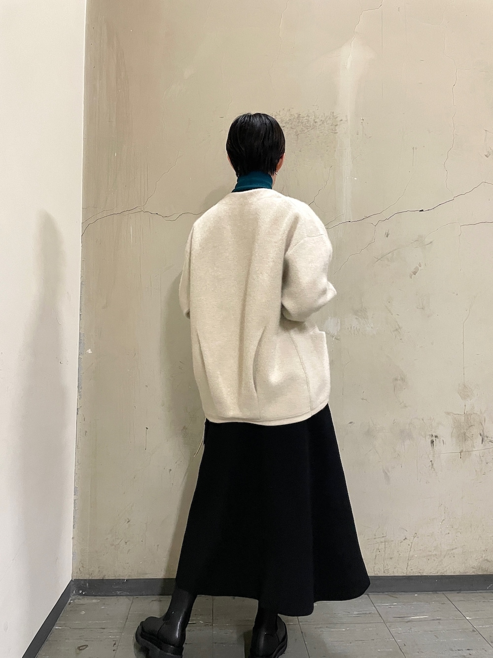 ブラック系のスカート、グリーン系のニット/セーター、ブラック系のブーツを着用したレディースの秋コーディネートの3枚目の写真