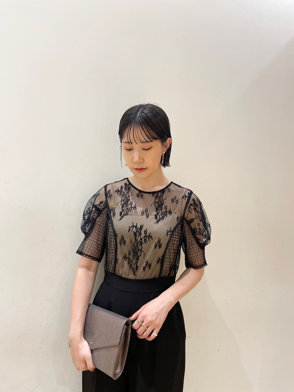 シルバー系のハンドバッグ、シルバー系のパンプス、ブラック系のパンツドレスを着用したレディースの夏コーディネートの6枚目の写真