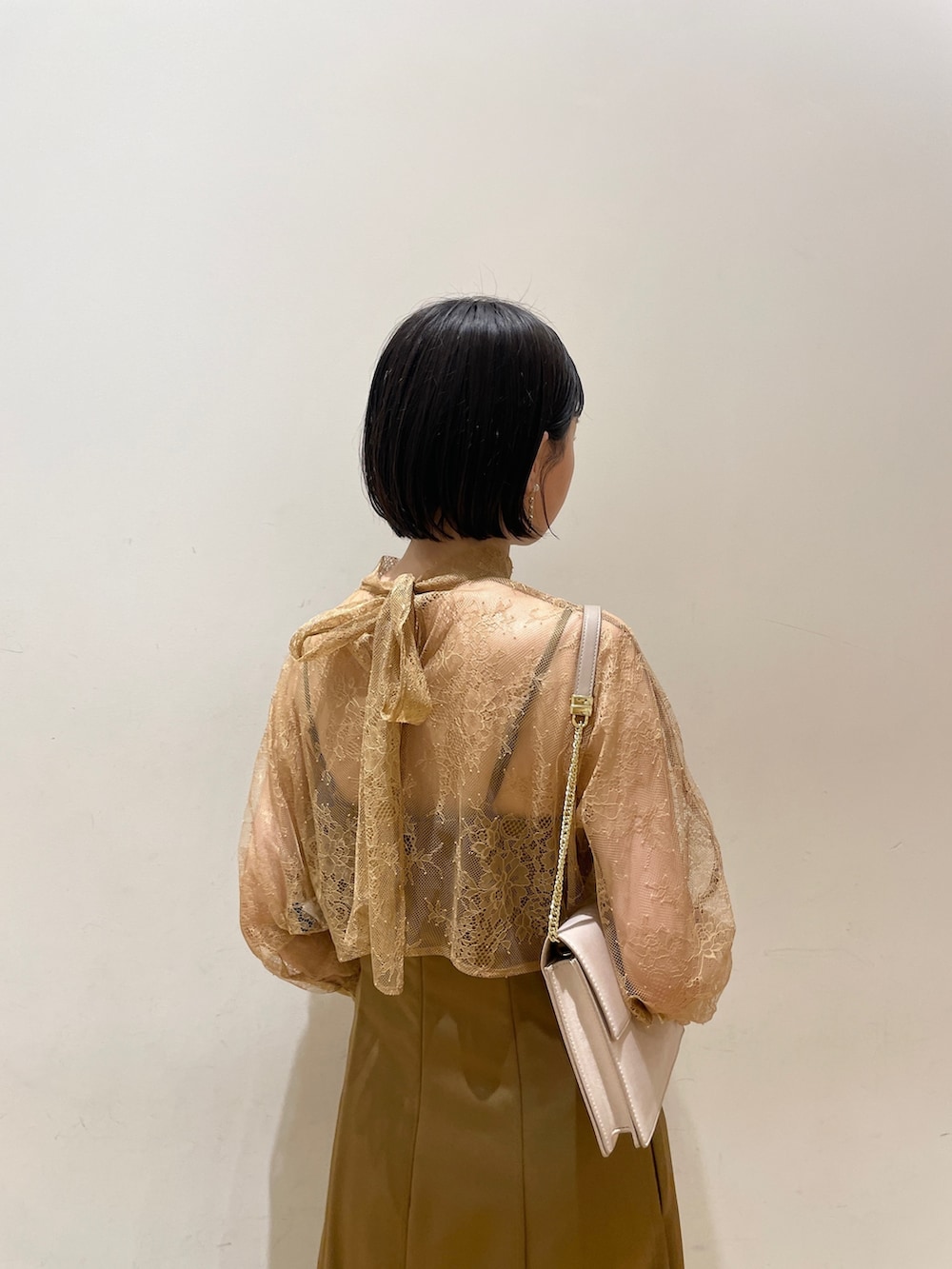 ブラウン系のドレス、ベージュ系のクラッチバッグ、ベージュ系のパンプスを着用したレディースの夏コーディネートの7枚目の写真