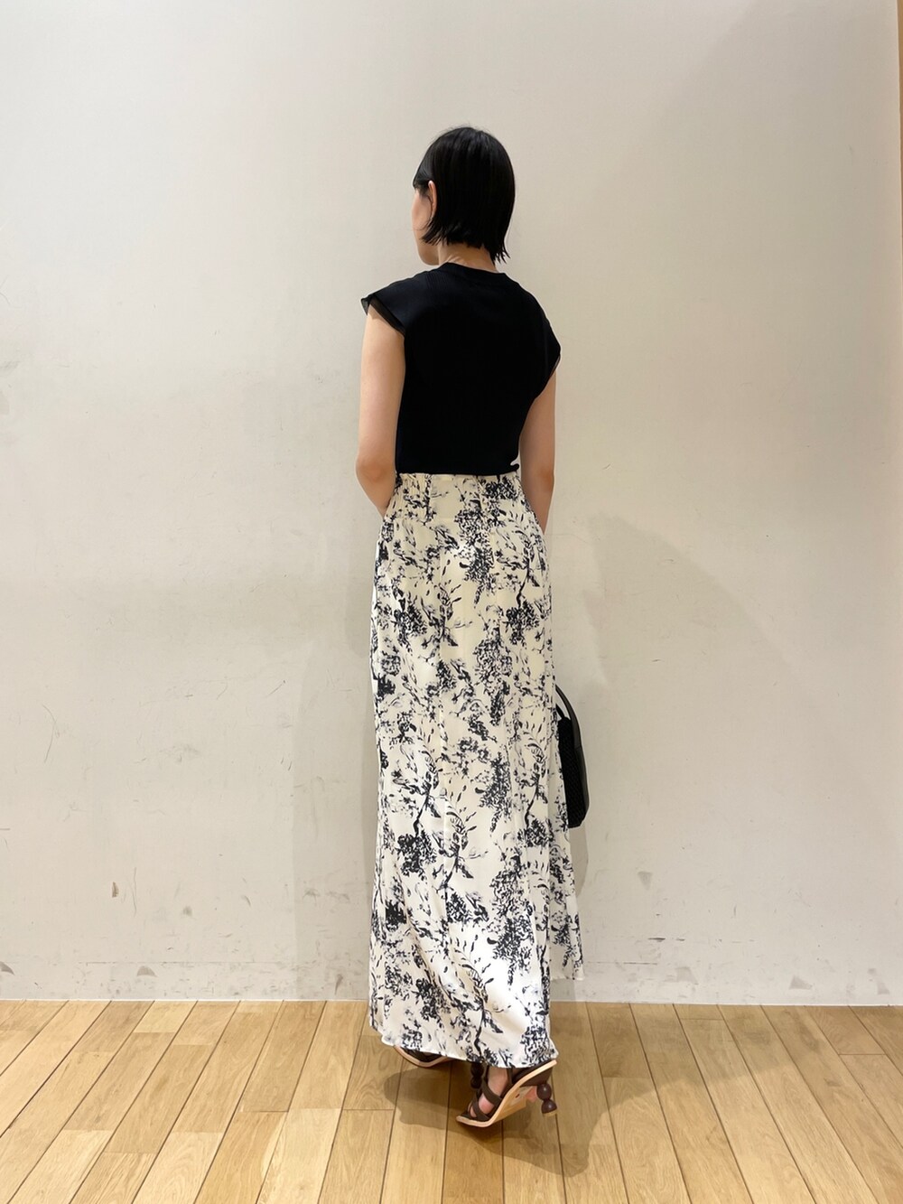 ブラック系のニット/セーター、ブルー系のスカート、ブラック系のハンドバッグを着用したレディースの夏コーディネートの4枚目の写真