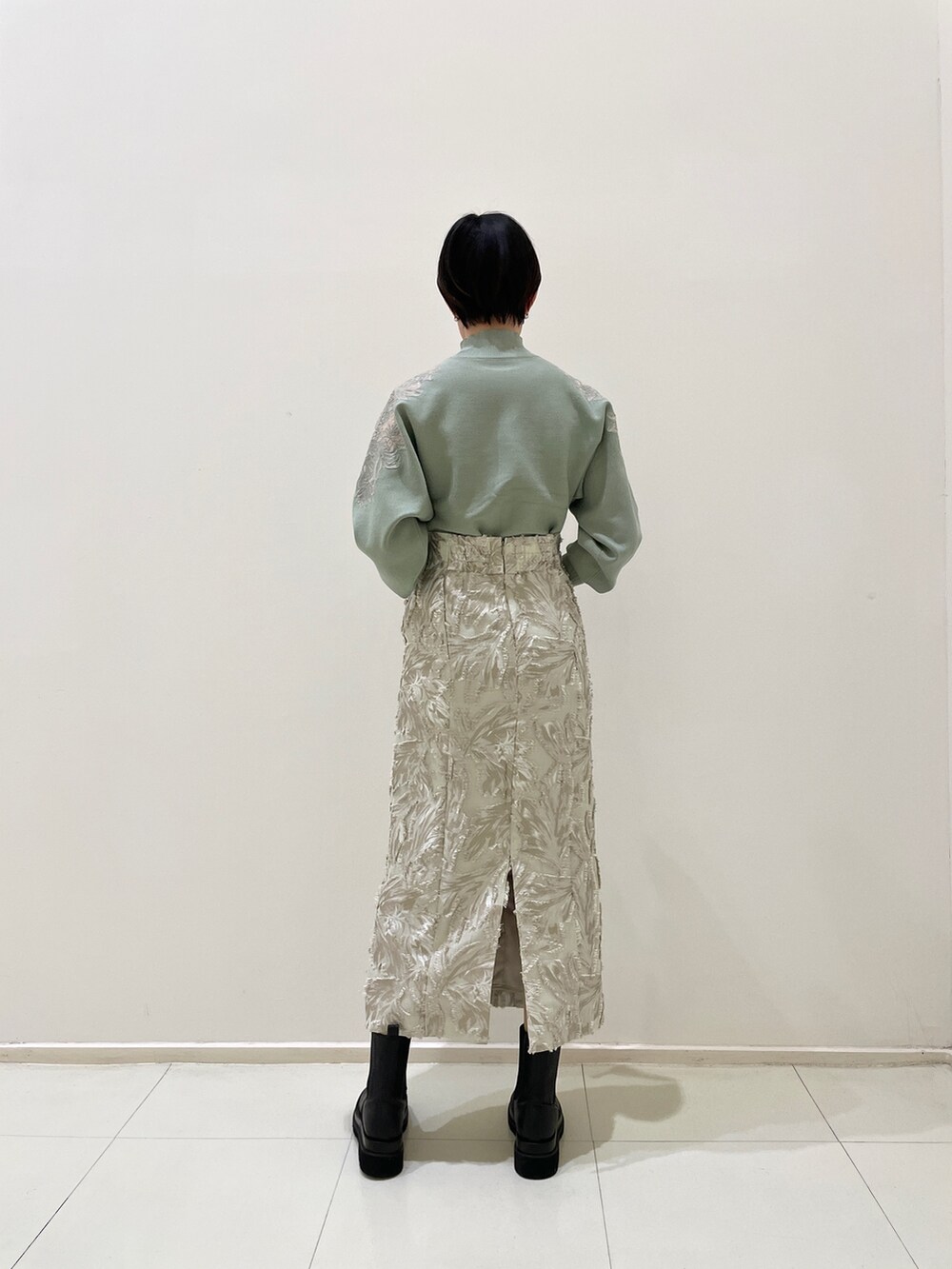 ベージュ系のスカート、グリーン系のニット/セーター、ホワイト系のハンドバッグを着用したレディースの冬コーディネートの3枚目の写真