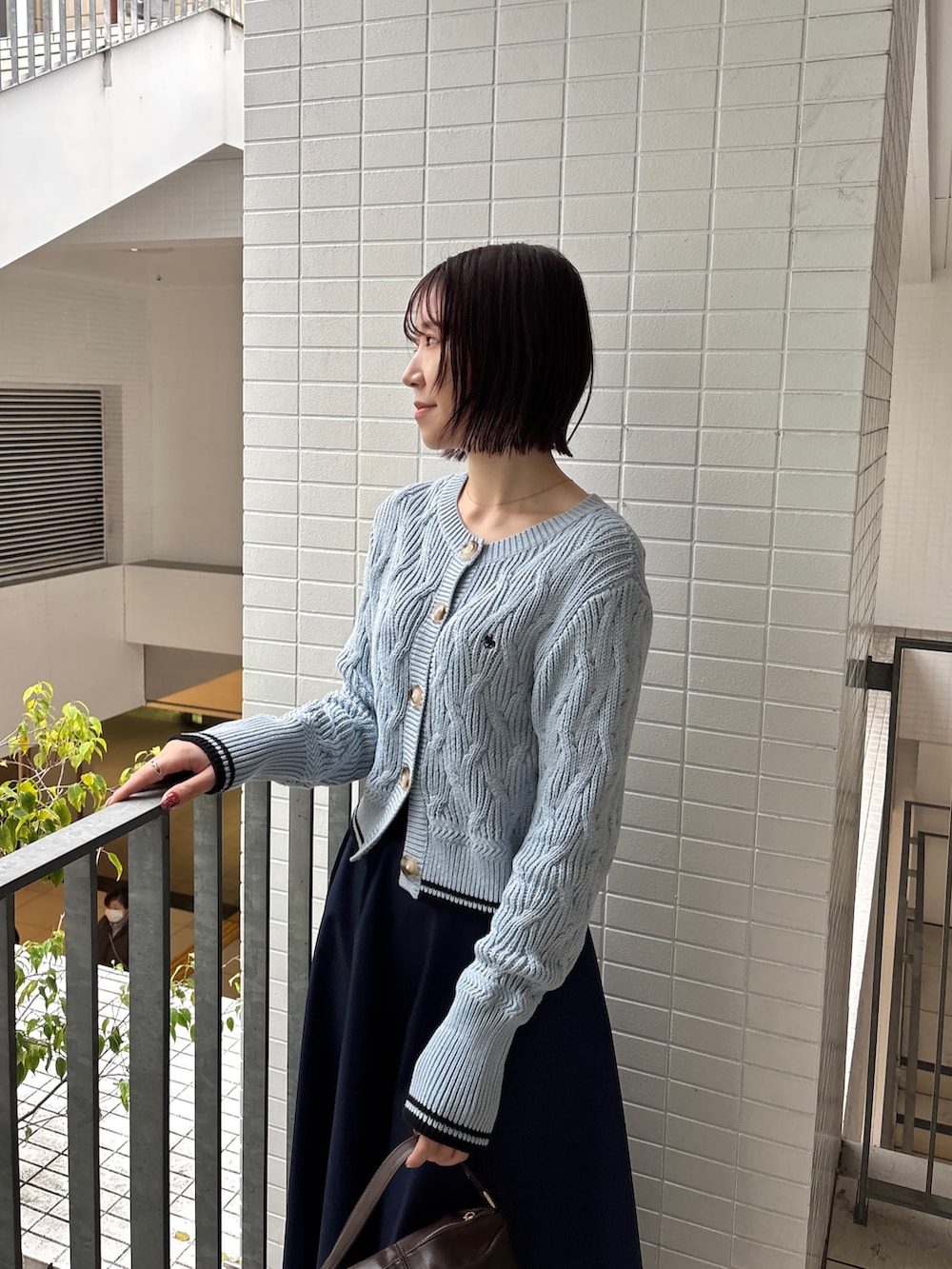 ブルー系のスカート、ブルー系のワンピース、ブラウン系のハンドバッグを着用したレディースの春コーディネートの4枚目の写真