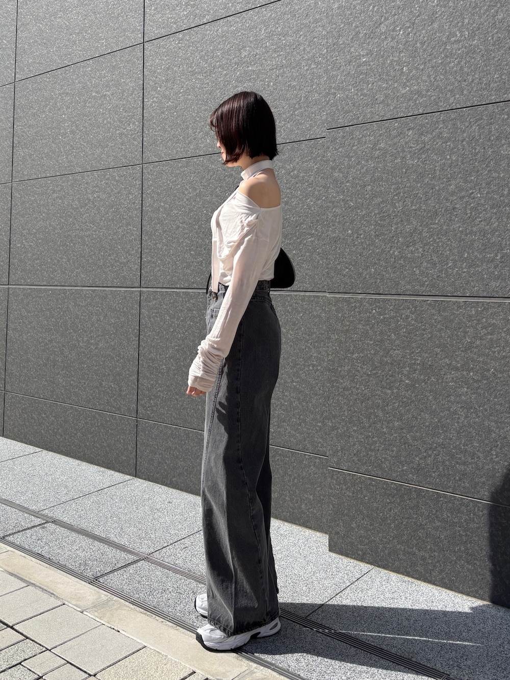 ブラック系のデニムパンツ、ホワイト系のTシャツ/カットソー、ブラック系のハンドバッグを着用したレディースの春コーディネートの3枚目の写真