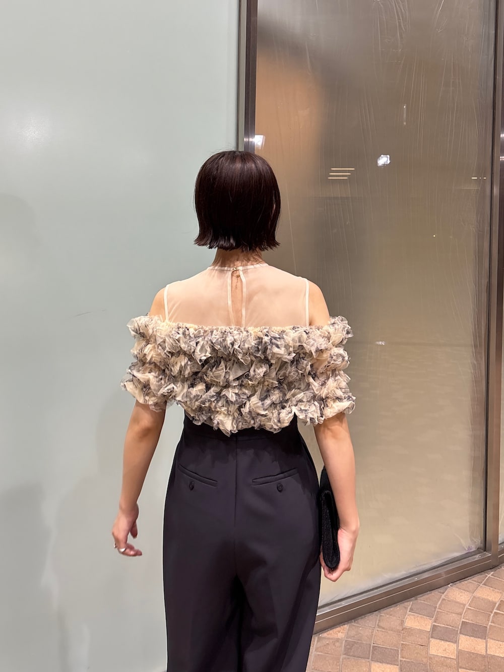 グレー系のパンツドレス、ブラック系のクラッチバッグ、ブラック系のパンプスを着用したレディースの夏コーディネートの7枚目の写真