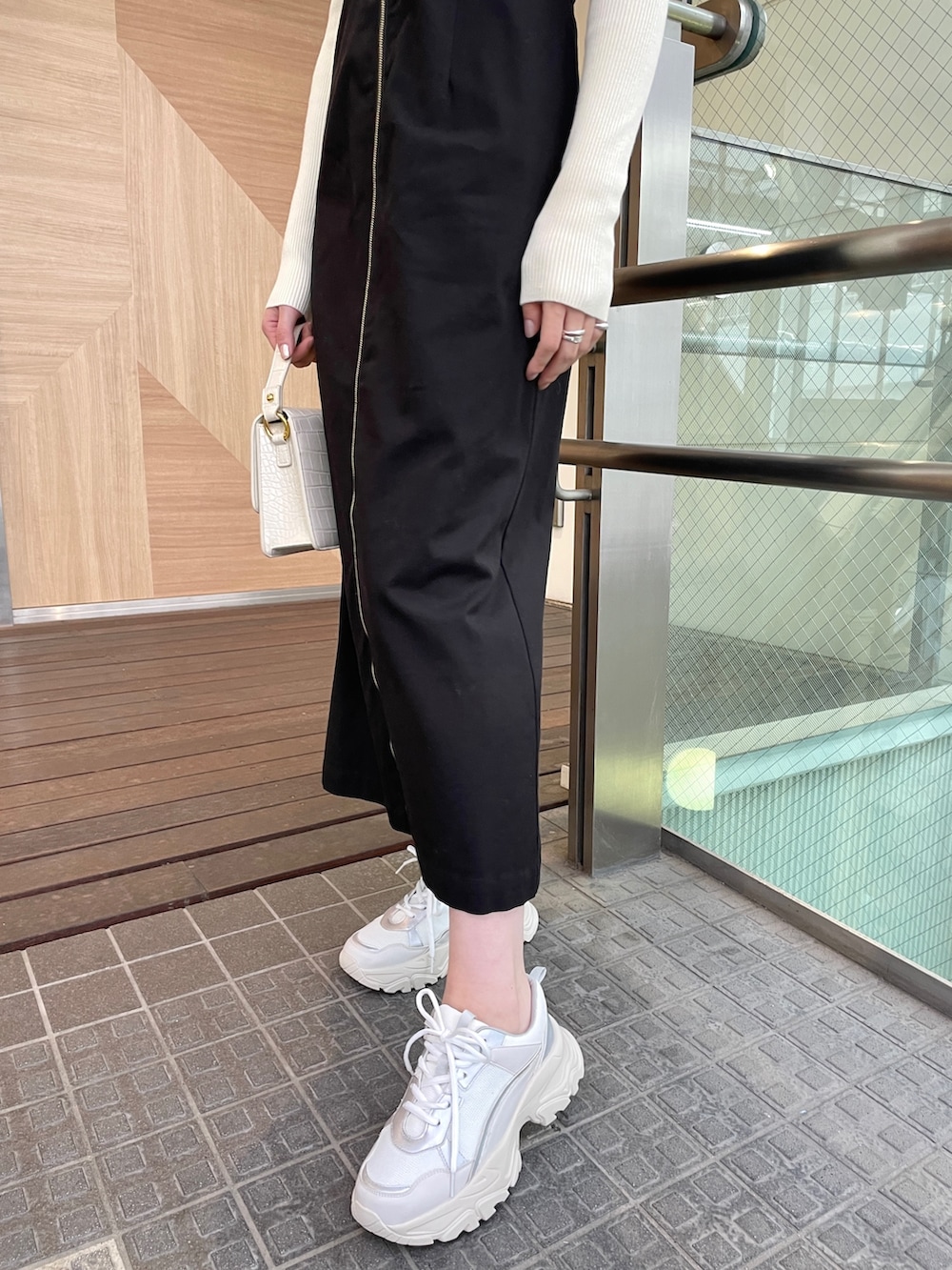 ブラック系のジャンパースカート、ホワイト系のショルダーバッグ、ホワイト系のニット/セーターを着用したレディースの春コーディネートの7枚目の写真