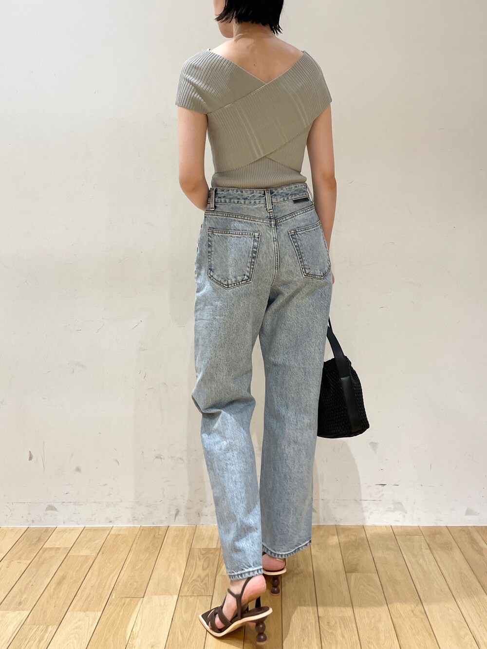 グリーン系のニット/セーター、ブルー系のデニムパンツ、ブラック系のハンドバッグを着用したレディースの夏コーディネートの4枚目の写真