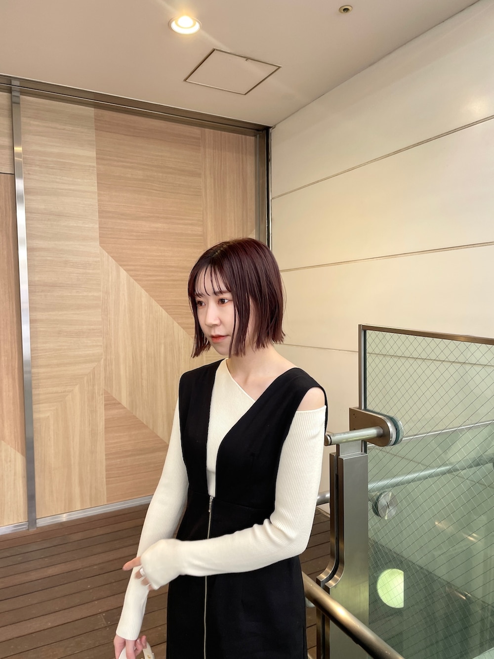 ブラック系のジャンパースカート、ホワイト系のショルダーバッグ、ホワイト系のニット/セーターを着用したレディースの春コーディネートの5枚目の写真