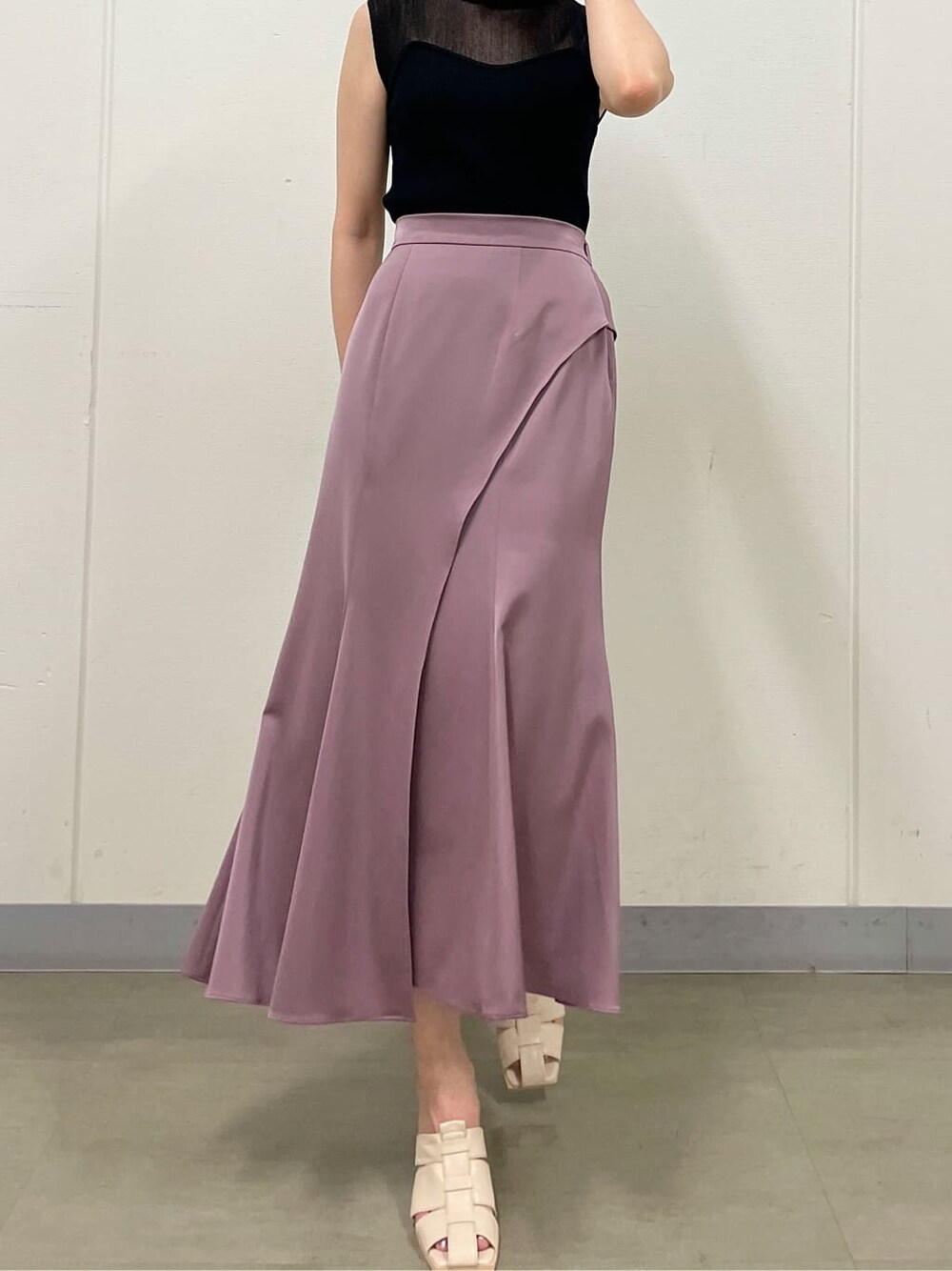 ピンク系のスカート、ホワイト系のサンダル、ブラック系のニット/セーターを着用したレディースの夏コーディネートの3枚目の写真