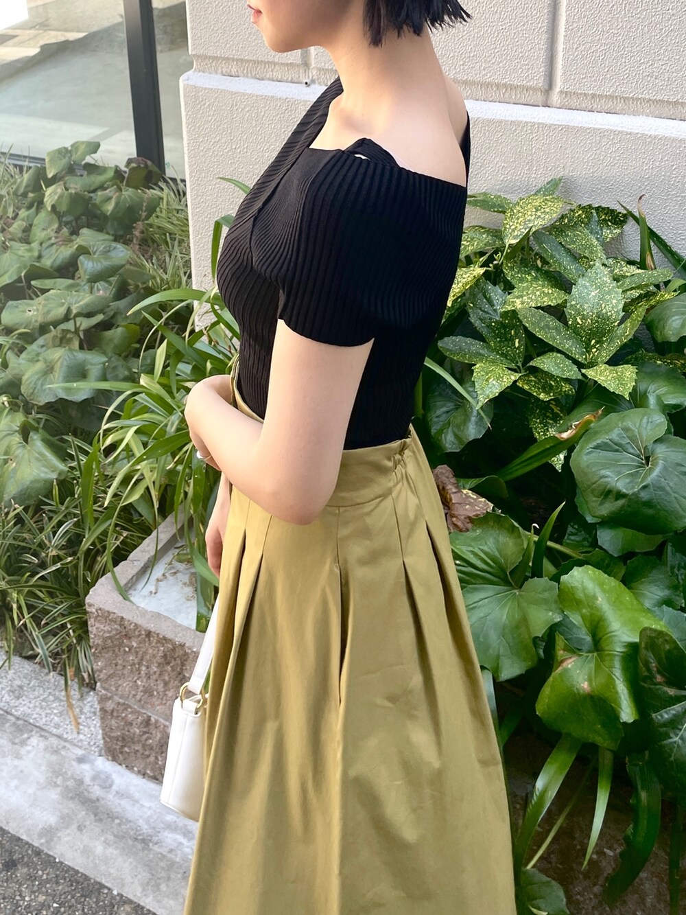 ブラック系のニット/セーター、イエロー系のスカート、ホワイト系のハンドバッグを着用したレディースの夏コーディネートの6枚目の写真