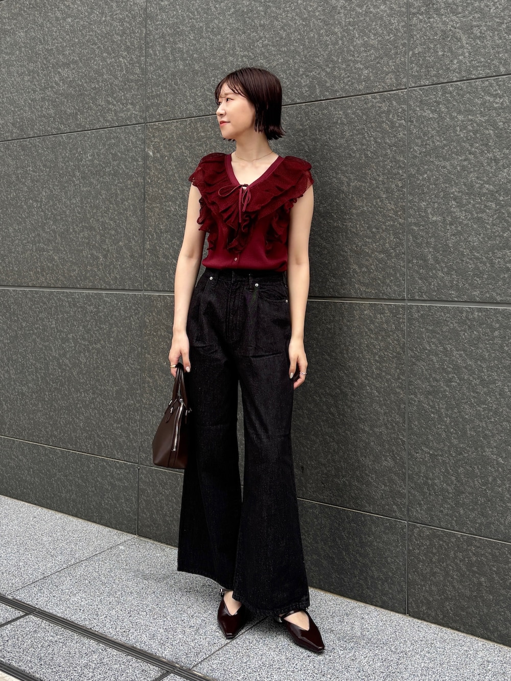 ブラウン系のボストンバッグ、ブラック系のデニムパンツ、ブラウン系のパンプスを着用したレディースの夏コーディネートの2枚目の写真