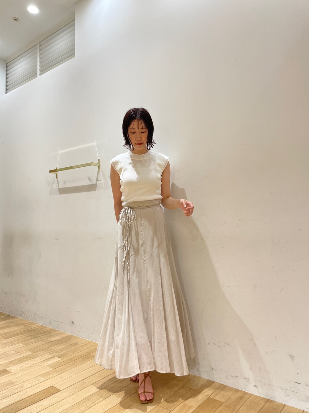 イエロー系のサンダル、グレー系のスカート、ホワイト系のニット/セーターを着用したレディースの夏コーディネートの2枚目の写真