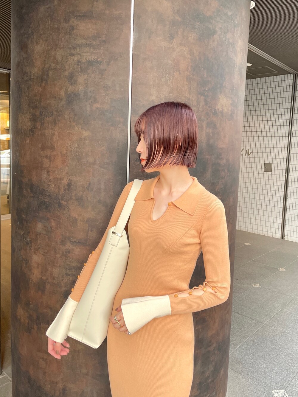 オレンジ系のワンピース、ホワイト系のショルダーバッグ、ブラック系のスニーカーを着用したレディースの冬コーディネートの5枚目の写真