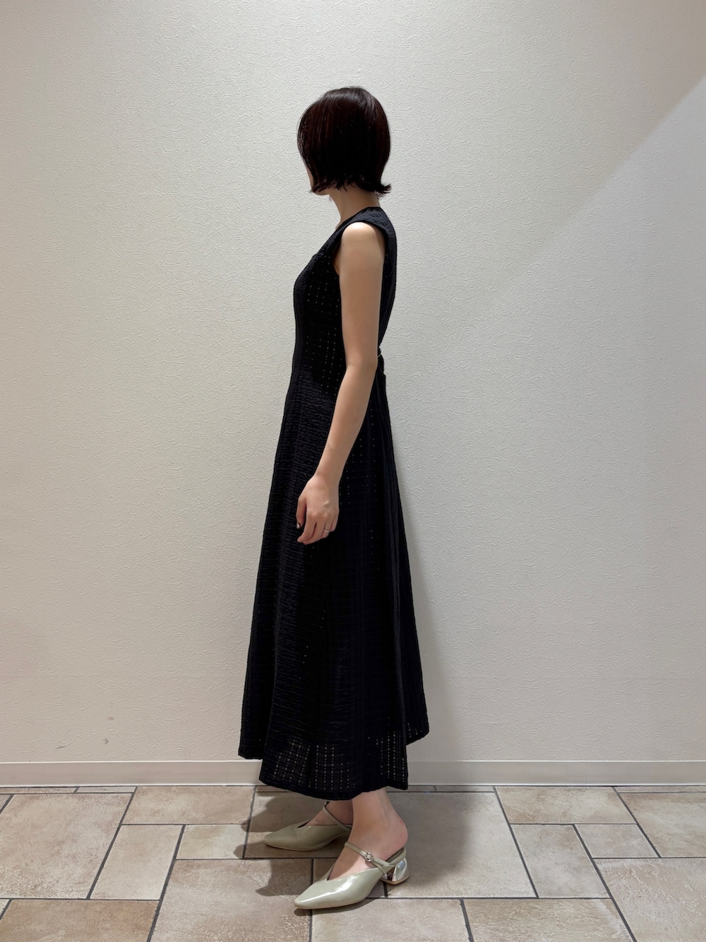 ブラック系のワンピース、ブラック系のハンドバッグ、グリーン系のパンプスを着用したレディースの夏コーディネートの3枚目の写真