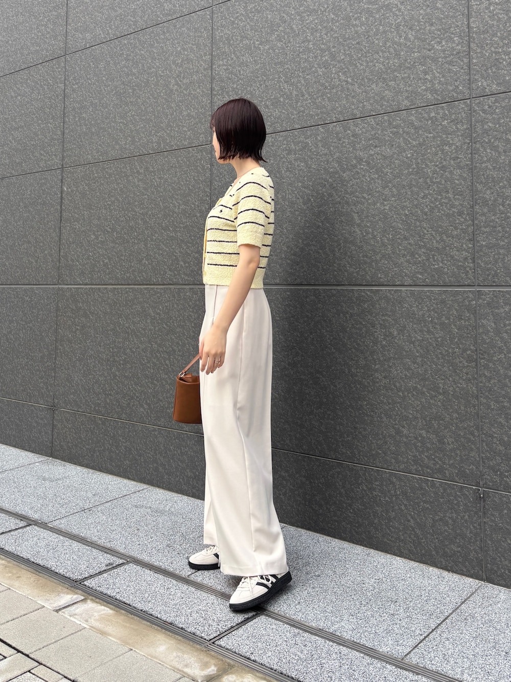 イエロー系のニット/セーター、ホワイト系のその他パンツ、イエロー系のハンドバッグを着用したレディースの春コーディネートの2枚目の写真