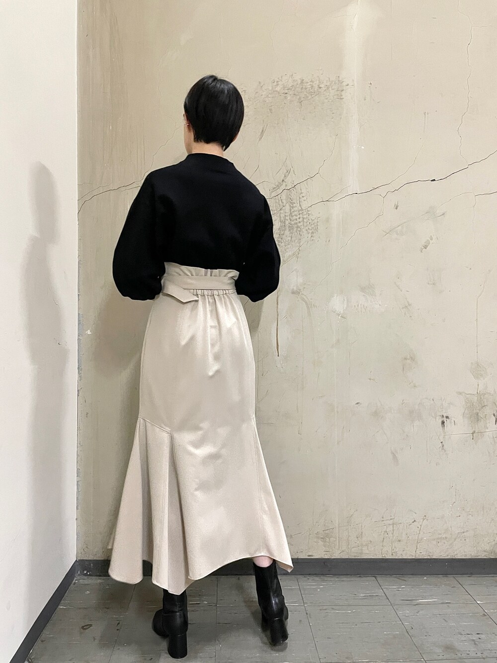 ベージュ系のスカート、ブラック系のニット/セーター、ブラック系のブーツを着用したレディースの秋コーディネートの5枚目の写真