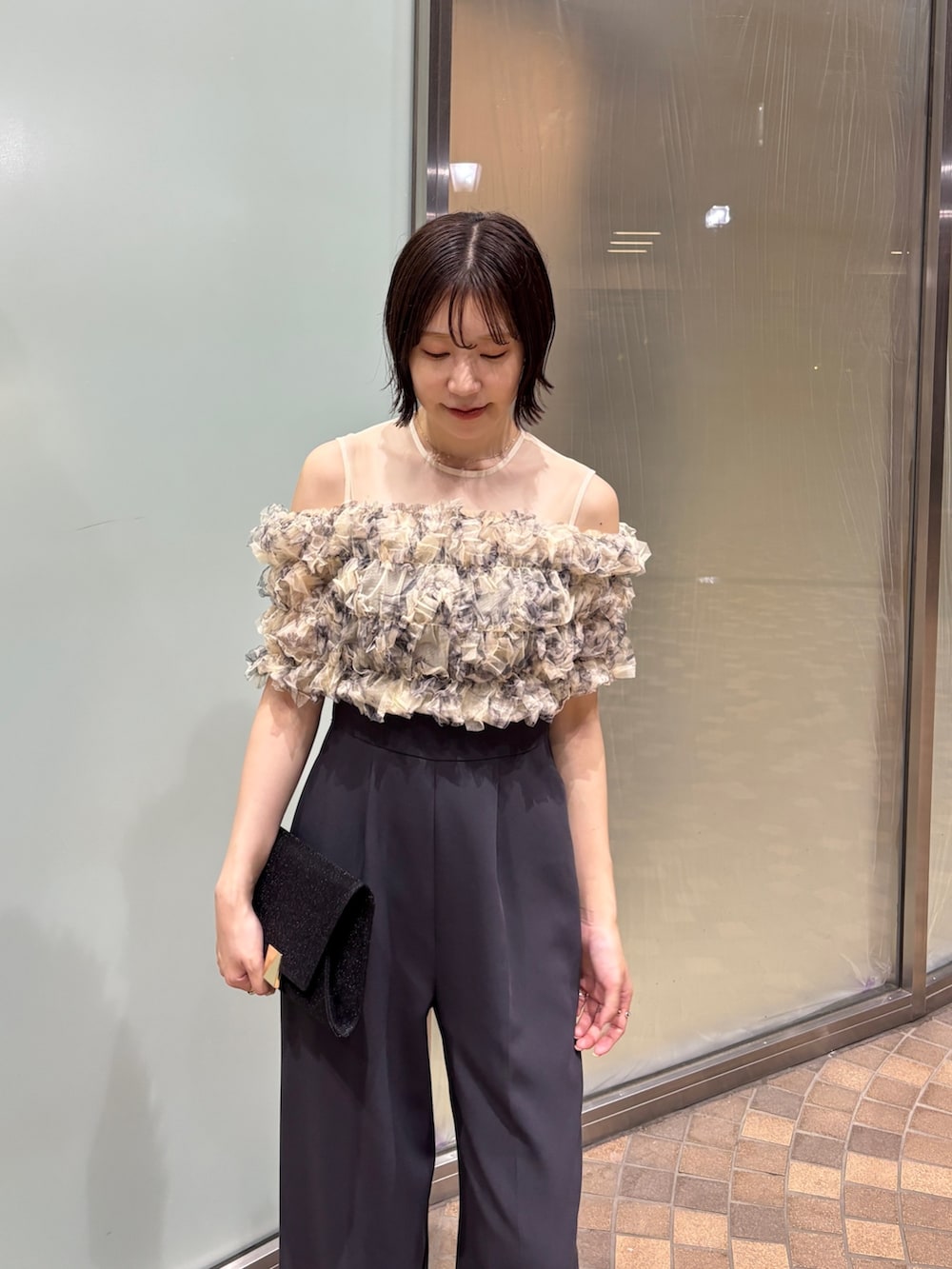 グレー系のパンツドレス、ブラック系のクラッチバッグ、ブラック系のパンプスを着用したレディースの夏コーディネートの6枚目の写真