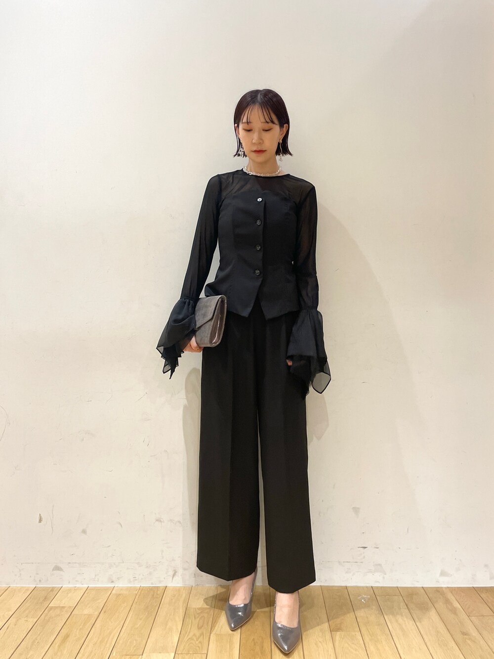 シルバー系のハンドバッグ、シルバー系のパンプス、ブラック系のパンツドレスを着用したレディースの秋コーディネートの2枚目の写真