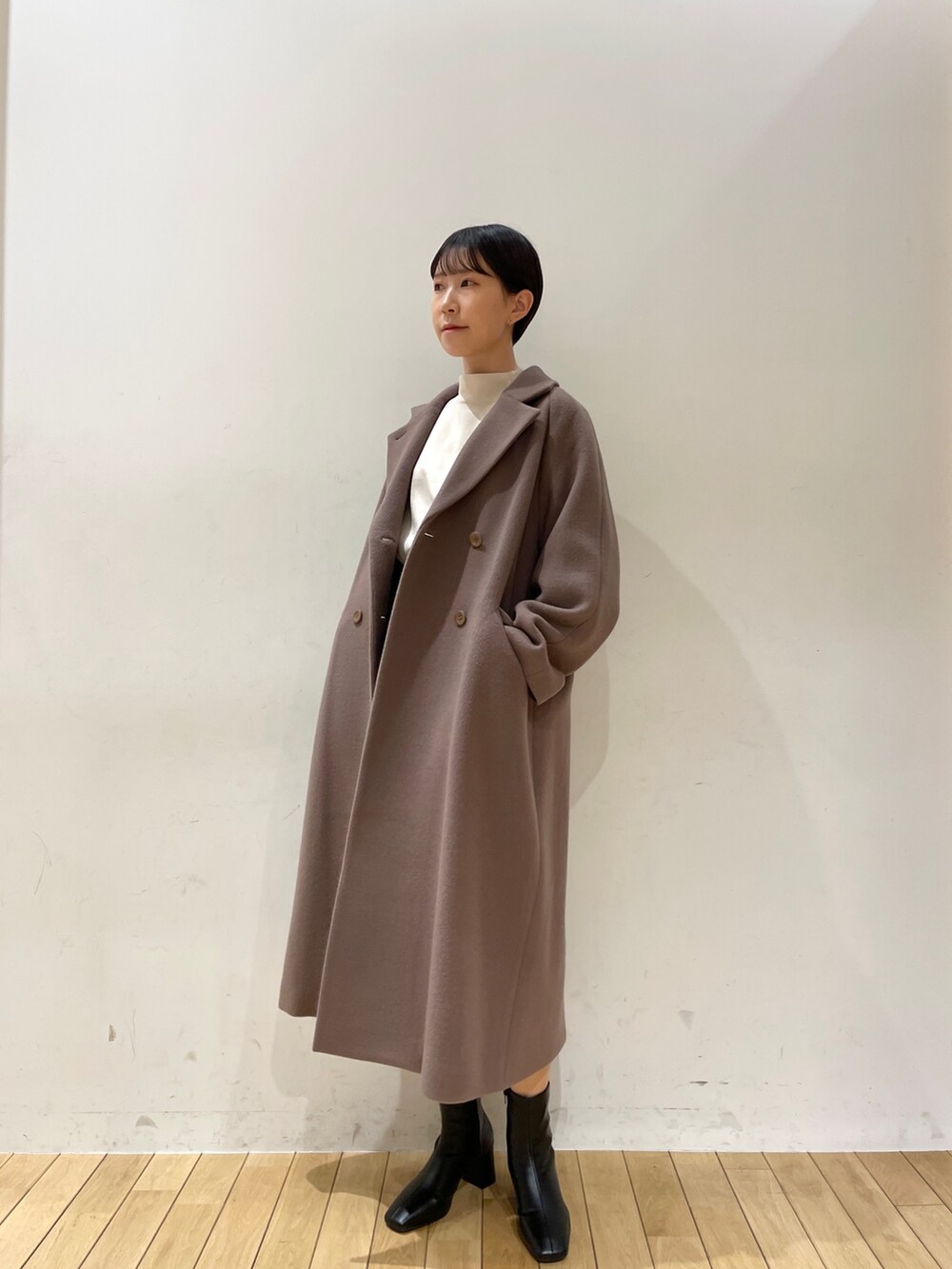 ホワイト系のニット/セーター、ブラック系のスカート、ブラック系のブーツを着用したレディースの冬コーディネートの2枚目の写真