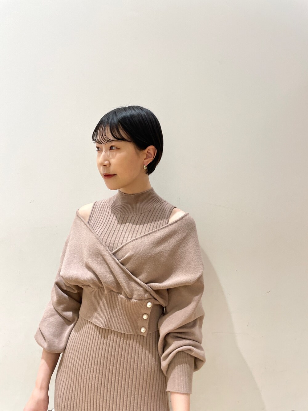 ベージュ系のワンピース、ホワイト系のハンドバッグ、ブラック系のブーツを着用したレディースの冬コーディネートの7枚目の写真