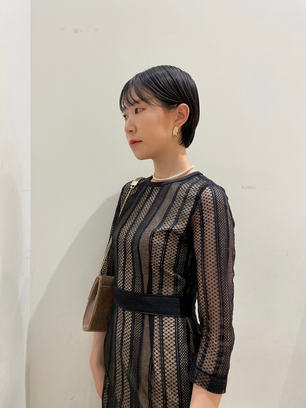 ブラック系のドレス、ゴールド系のハンドバッグ、ゴールド系のパンプスを着用したレディースの冬コーディネートの6枚目の写真