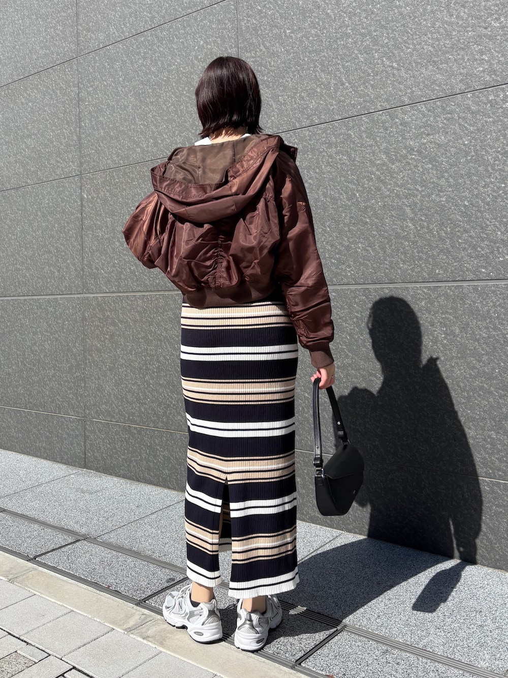 ベージュ系のワンピース、ブラック系のハンドバッグ、ブラウン系のブルゾンを着用したレディースの春コーディネートの4枚目の写真